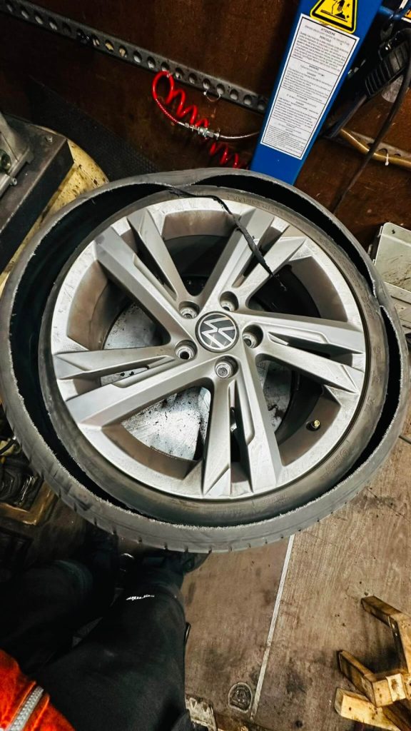 A blown-out car tyre being replaced by a mobile fitter inside a service van in Birmingham.